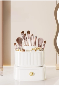 Rotating makeup brush organizer with vertical striped design and a gold handle drawer