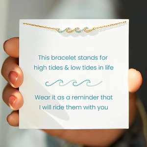Gros plan détaillé du bracelet vague doré avec pierres bleues et carte de message