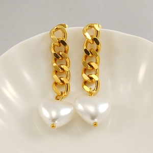 Detail view of 18K gold-plated chain earrings with white heart pearl pendants on a ceramic tray