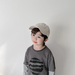 Détail d'un garçon portant un t-shirt gris foncé et une casquette de baseball beige