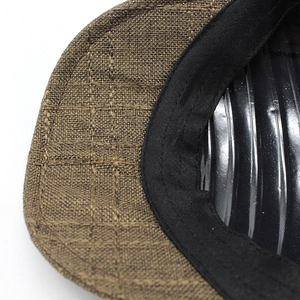 Close-up of tan mesh weave fabric and black sweatband detail on a breathable flat cap