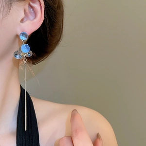 Detail of long silver tassel earrings with transparent blue resin beads on model