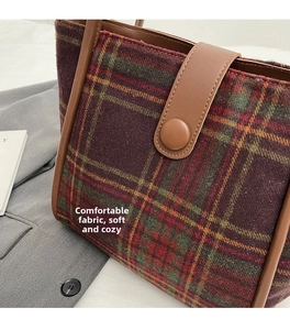 Detail of red and green plaid wool tote bag with brown leather trim and magnetic closure