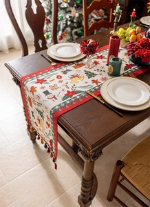Close-up of Christmas table runner with jacquard snowman and tree patterns and tassel edge