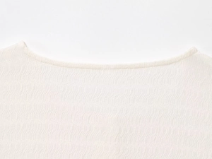 Primo piano del tessuto a maglia bianco con motivo a onde e dettaglio dello scollo a barca