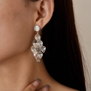 Close-up of silver hollow leaf tassel earrings with metallic finish on a model