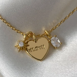 Gold Mom necklace with zircon star and heart charms on elegant white silk background