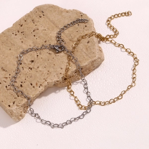 Detail of gold and silver heart-shaped link anklets with lobster clasp on a stone base