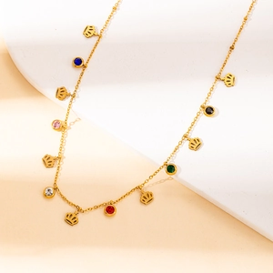 Detail shot of golden necklace with crown pendants and colorful zircon stones
