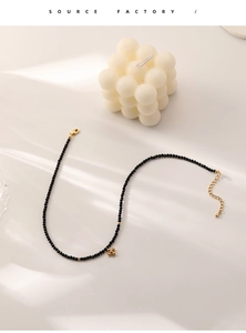 Detail of black beaded choker with golden flower charm and adjustable lobster clasp