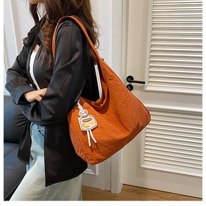 Close-up of bright orange nylon tote bag featuring a cute cartoon fashion bag pendant