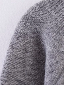 Detail of soft fuzzy texture and fine stitching on a grey knit cardigan sweater