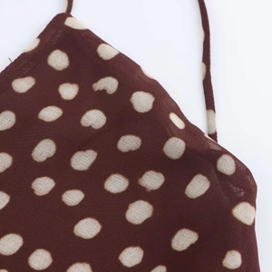 Close-up of brown and beige polka dot chiffon fabric texture with soft lighting
