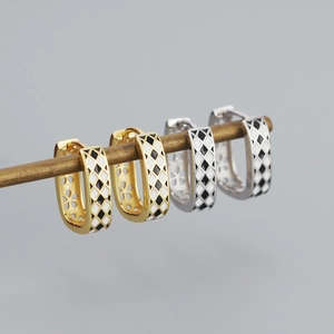 Macro detail of gold and silver S925 U-shaped earrings with black and white enamel pattern