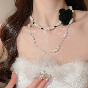 Detail of double-layer pearl necklace with a vintage black knit rose on a female model