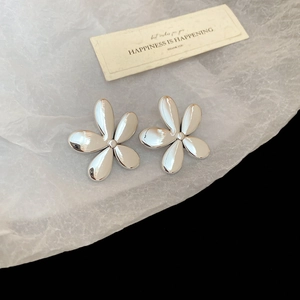 Détail de boucles d'oreilles fleur en métal brillant avec cinq pétales arrondis