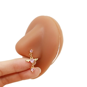Detailed view of heart-shaped pink zircon nose stud with gold angel wings on model