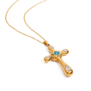 Golden cross necklace with blue square stone and clear zircon accents on white background