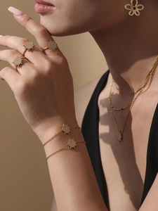 Close-up of gold stainless steel sunburst jewelry set with zircons worn by a model