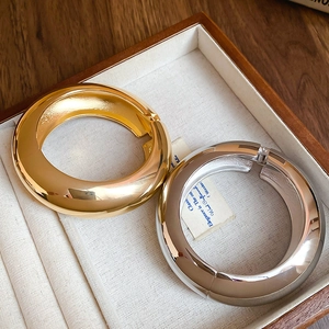 Detailed view of polished gold and silver adjustable bracelets in a wooden jewelry box