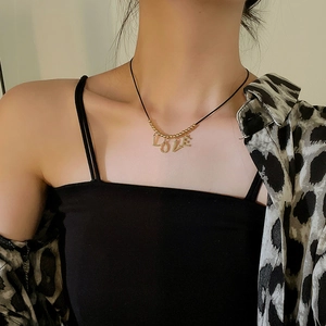 Detail of LOVE pendant necklace with golden metal beads and black cord on female model