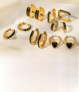 Macro shot of gold-plated geometric heart earrings with black zircon inlays