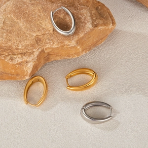 Detail of polished gold and silver U-shaped geometric earrings on textured stone base