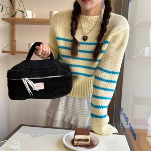 Detail of plush black faux fur makeup bag with dual zippers and woven brand label