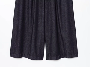 Detailed macro view of dark blue denim fabric texture and wide-leg hem stitching