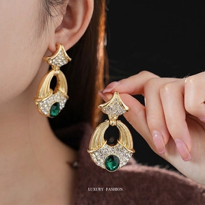 Vintage gold geometric earrings featuring emerald stones and diamonds worn by model