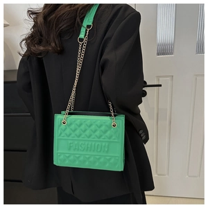 Detail of green quilted crossbody bag with metal chain strap and fashion embossed lettering