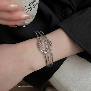 Close-up of a silver multi-layer twisted bangle with interlocking ring detail and polished finish