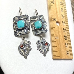 Detail view of vintage gold wire flower earrings with green gemstone and measurement ruler
