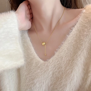 Minimalist gold titanium steel ball necklace shown on a model with a soft V-neck sweater