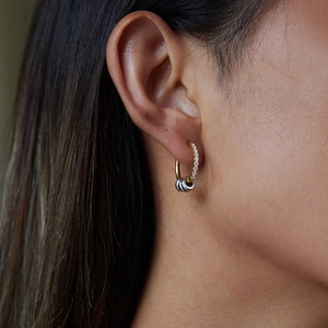 Macro view of gold hoop earrings with sparkling diamond and tricolor ring pendants