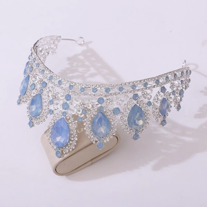 Detailed view of a silver bridal crown with light blue gemstones on a beige display stand