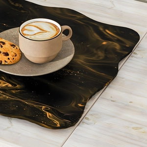 Irregular irregular black and gold marble pattern coaster on a light wood background