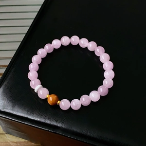 Detailed view of pink beaded bracelet with dark brown accent bead on black leather display