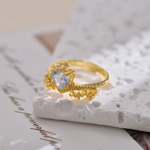 Golden crown ring with heart-shaped clear gemstone and vintage floral carvings