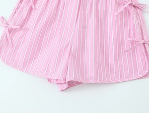Detail of pink and white striped cotton shorts featuring delicate side bow drawstring ties