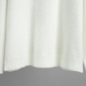 Close-up of white plush knit sweater hem featuring ribbed cuffs and soft fuzzy texture