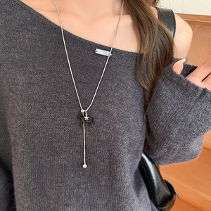 Detail showing a silver chain necklace with a black horse pendant and a small gold star charm