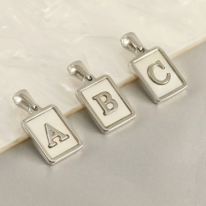Vue détaillée macro de pendentifs carrés argentés lettres A, B et C avec incrustation