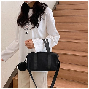Detailed view of black nylon tote bag with round coin purse accessory on wooden steps