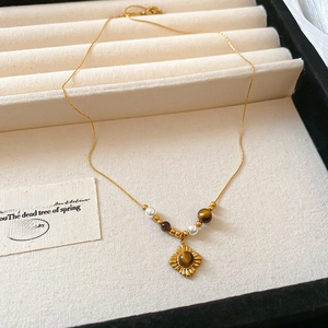 Macro detail of gold-plated sunflower necklace with tiger eye stone and small pearls