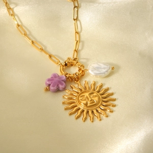 Detail von Sonnenanhänger, lila Blumenperle und Barockperle an goldener Halskette