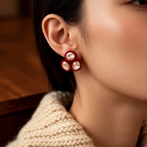 Close-up of red flocked oval earrings with sparkling crystals worn by a model