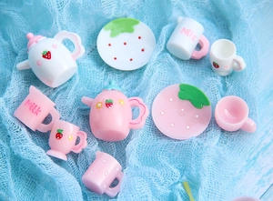 Miniature pink strawberry teapot and teacup resin set displayed on blue mesh background