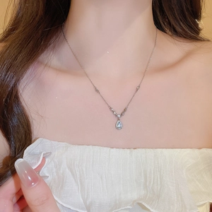 Close-up of a silver water drop pendant necklace with shimmering crystals on a female model