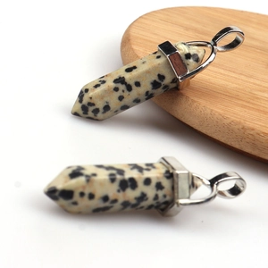 Close-up of Dalmatian stone hexagonal prism pendants on a wooden display stand